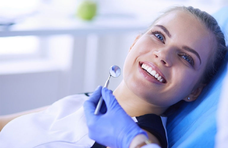 a woman smiles confidently after receiving same-day emergency dental treatment